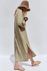 Vestido camisero blanco confeccionado en lino, de corte recto y largo midi. Presenta cuello camisero, mangas 3/4 con puños abotonados, cierre frontal con botones y abertura en el ruedo.