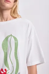 Remera blanca de corte amplio con estampado abstracto de flores en tonos rosa, rojo y verde.