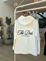 Hoodie negro de corte oversize, con capucha, bolsillo frontal y estampado blanco en la espalda con la inscripción "The Dolls The Dolls VIP CLUB".