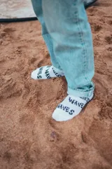 Pack de dos pares de medias blancas con texto 'Glassy Waves' estampado en negro.