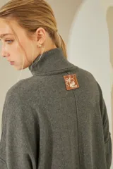 Sweater negro oversize de tejido de punto, con cuello alto y detalle de costuras a la vista.