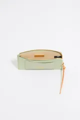 Monedero Bimba y Lola de piel color verde claro con cierre de cremallera y tirador de cordón naranja. Cuenta con logo metálico y tarjetero interior.