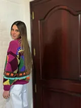 Sweater de lana merino color crema con cuello alto y diseño con motivos geométricos en amarillo, naranja, violeta y negro.