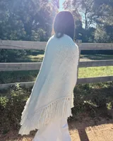 Ruana tejida a mano en lana Merino hilado grueso, con diseño en V y flecos.