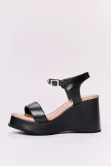 Sandalias negras de cuero con plataforma y taco ancho. Tira ancha sobre los dedos y tira con hebilla al tobillo.