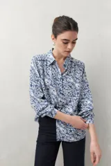 Camisa de manga larga con estampado paisley en tonos azul y blanco, cuello camisero y cierre frontal con botones.