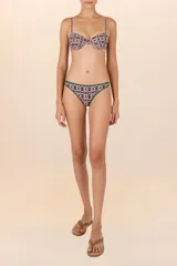 Calzón de bikini verde oscuro con estampado geométrico de círculos blancos y rosas. Tiene corte a la cadera, cobertura chica y ribete verde.