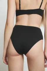 Conjunto de lencería color piel, compuesto por un corpiño triangular con breteles finos y detalle de tul en el escote, y una bombacha vedetina alta con detalle de tul en los laterales.