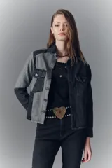 Campera recta de denim rígido negro con recortes en gris. Tiene bolsillos con solapa y botones metálicos.