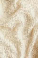Top color crema de punto con textura, escote barco, sin mangas y frunces laterales.