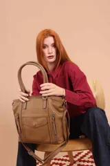 Cartera bandolera de símil cuero color marrón claro, con doble asa rígida y correa regulable. Presenta dos bolsillos frontales con cierre vertical y un bolsillo frontal con solapa y botón. Cuenta con dos divisiones internas.