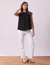Blusa negra de crepe con apliques de crochet en los hombros. Tiene cuello redondo, mangas cortas y espalda con abertura ojal y botones.