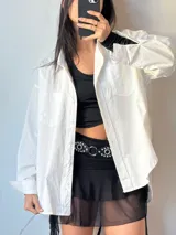 Camisa blanca de manga larga con cuello clásico y botones frontales.