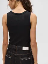 Musculosa crop de algodón, color azul grisáceo, con tejido acanalado (rib) y cuello redondo. Presenta un pequeño logo bordado en el centro del pecho.