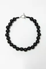 Collar doble con cadena de cuentas negras y dije transparente en forma de gota.