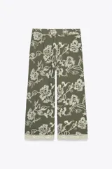 Pantalón de tiro alto color verde oliva con bordado floral blanco, bolsillos laterales ocultos, pernera ancha y terminación en guipur.
