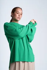 Sweater color beige de tejido de punto acanalado, con cuello redondo y mangas largas. Tiene corte holgado y aberturas laterales en el ruedo.