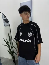 Remera negra de manga corta con cuello redondo y detalles en blanco en los hombros. Presenta un estampado con el logo de la marca en el frente.