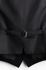 Chaleco de vestir negro con cuello en V, cierre de botones y bolsillos ribeteados. Espalda de tejido brillante con trabilla ajustable. Corte ajustado y forro interior.