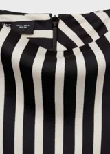 Blusa sin mangas de tejido fluido satinado con estampado de rayas verticales en blanco y negro, cuello Perkins y cierre de cremallera en la parte posterior.