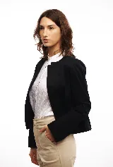 Chaqueta negra corta con cuello mao y volado en el bajo. Puede usarse como blazer doblando las solapas.