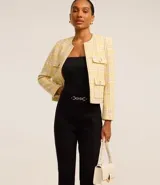 Pantalón flare de punto roma color beige, con detalle metálico en la cintura y cierre frontal.