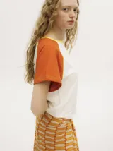 Remera colorblock con mangas ranglan color naranja, cuerpo blanco y cuello amarillo.