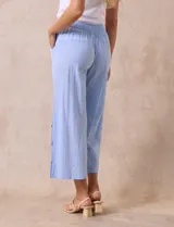 Pantalón blanco de algodón con pretina elastizada, bolsillos inclinados y ruedo lateral con tajo y botones.