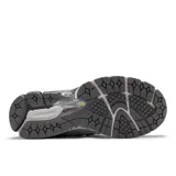 Championes New Balance modelo 1906R, color blanco y gris con detalles en amarillo neón y negro. Presentan una parte superior de malla perforada con superposiciones sintéticas, logo 'N' lateral en amarillo neón, y entresuela con tecnologías ABZORB SBS y N-ergy.