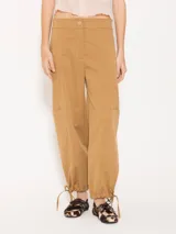 Pantalón cargo color camel confeccionado en poplin asargado. Incluye cuatro bolsillos plaqué con refuerzos triangulares en boca de bolsillo trabajados en hilo a contratono crudo. El ruedo lleva jareta para ajustar y abuchonar con lazo.