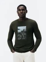 Remera verde militar de manga larga con estampa rectangular frontal de una moto antigua.