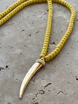 Collar de cuentas redondas color amarillo con dije colgante dorado en forma de cuerno.