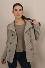 Chaqueta corta de lana color beige con diseño de espiga, doble abotonadura, cuello solapa y bolsillos ojal. Presenta apliques de tela en los hombros.