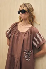 Vestido corto color crudo con bordado de hojas en el ruedo y en las mangas.