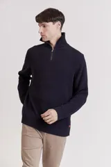 Sweater de punto color crema con cuello alto y cierre de cremallera parcial. Diseño de corte holgado y mangas largas.