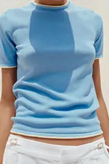 Remera blanca de punto con cuello redondo y mangas cortas con ribete negro en cuello, mangas y ruedo.