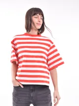 Remera blanca con rayas horizontales rojas, de corte holgado y mangas cortas.