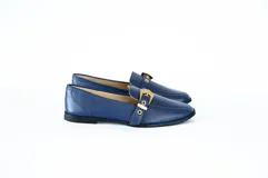 Mocasín azul con detalle de hebilla dorada.