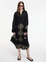 Vestido camisero negro con bordados dorados de motivos geométricos.