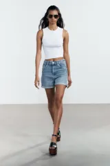 Bermuda de jean celeste, corte mom fit, tiro alto, con cinco bolsillos y ruedo doblado.