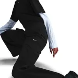 Pantalón negro de corte ancho con bolsillos cargo laterales y logo de Nike bordado en blanco.