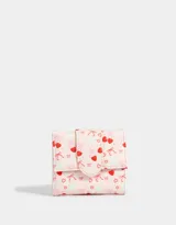 Billetera pequeña con solapa, color crema con estampado de corazones rojos, moños rosas y cerezas.