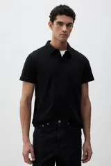 Chomba negra de piqué de algodón, corte slim fit, con cuello clásico, tapeta de dos botones y mangas cortas.