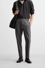 Pantalón color arena de corte recto, confeccionado en tejido elástico. Cuenta con cintura elástica ajustable con cordón, bolsillos laterales y bolsillos de vivo en la parte trasera.