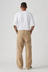 Pantalón de trabajo color beige, de corte recto y holgado, con bolsillos laterales y traseros.