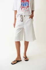 Bermuda blanca de denim, tiro bajo, con cuatro bolsillos, pasacintos, cartera con cierre y botón metálico.