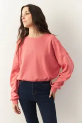 Buzo cropped de manga larga color rosado, con puños ajustados y cordones en la cintura.