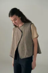 Chaleco marrón con solapas amplias y terminaciones envivadas. Diseño reversible y sin mangas.