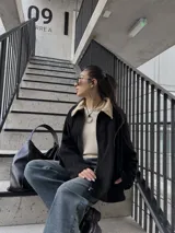Campera negra de pana con cuello beige, cierre frontal y bolsillos laterales.