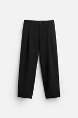 Pantalón negro de corte amplio, con pliegues en la parte delantera, bolsillos laterales y traseros de ojal.